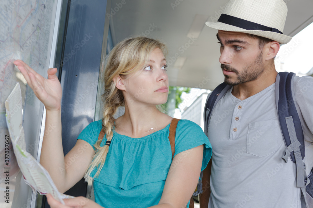 couple looking at public transport notice board couple looking at public transport notice board