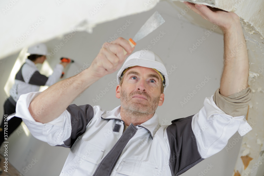 portrait of builder removing the wallpaper