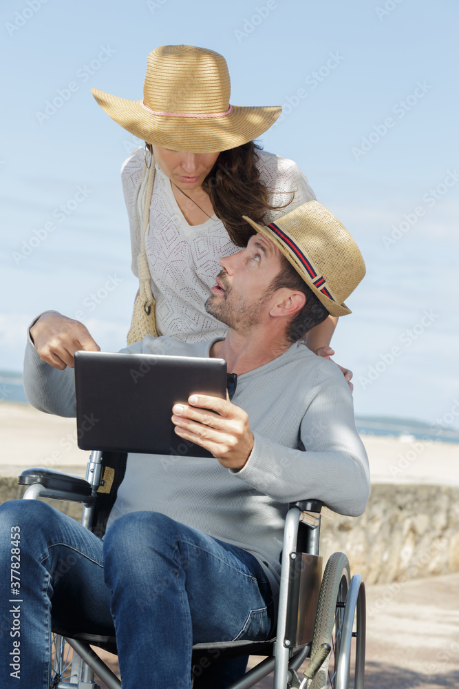 woman and man in a wheelchair looking at tablet