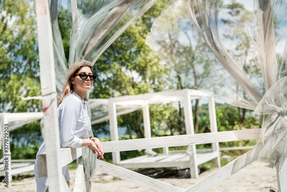 Naklejka premium pretty girl enjoy sunny summer day near lake in white gazebo