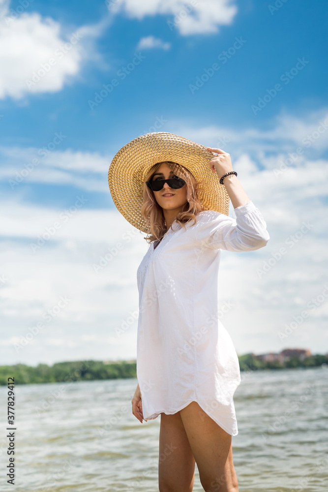 woman in white blouse and straw hat resting on a hot summer day walking on  lake