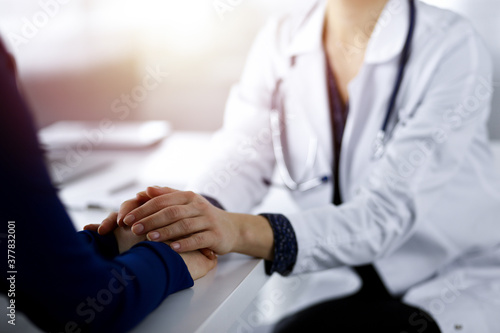 Unknown woman-doctor is reassuring her female patient  close-up. Physician is consulting and giving some advices to a woman in a sunny cabinet. Concepts of medical ethics and trust. Empathy in