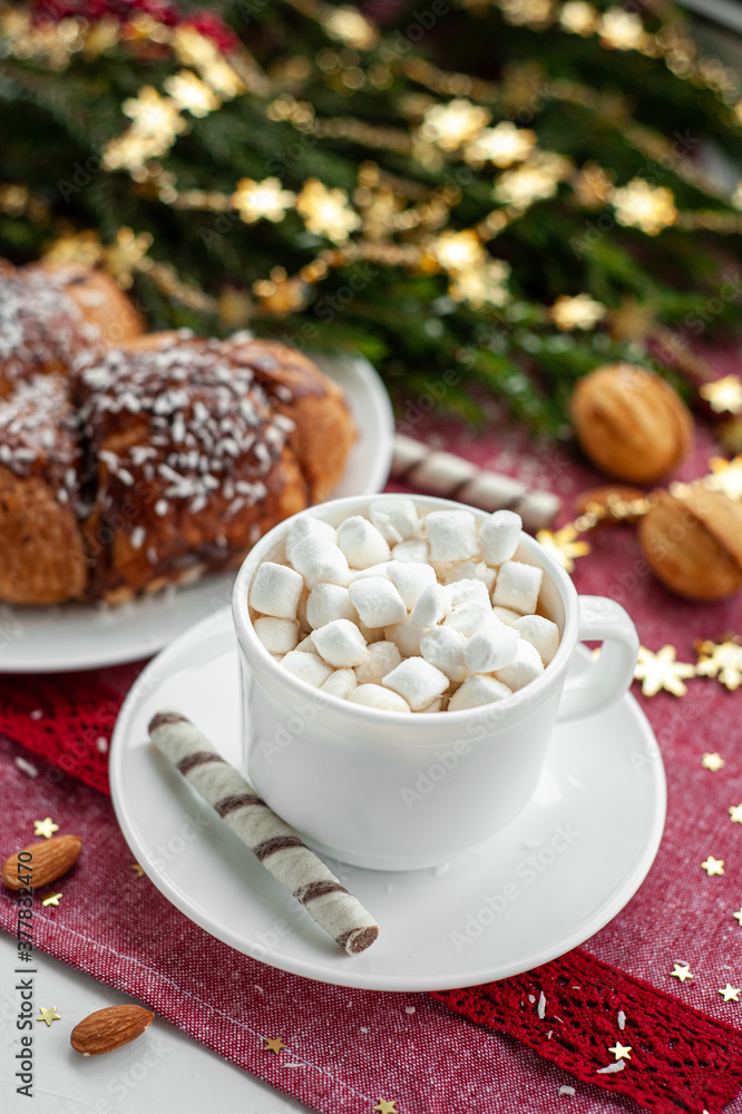 Christmas breakfast. Christmas morning. A cup of coffee or cocoa with marshmallows and sweets. On a red tablecloth next to a branch decorated with Christmas spruce. Selective focus. Christmas breakfast. Christmas morning. A cup of coffee or cocoa with marshmallows and sweets. On a red tablecloth next to a branch decorated with Christmas spruce. Selective focus.