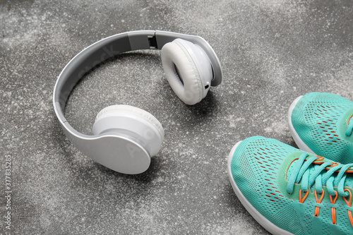 Sportive shoes and headphones on grey background