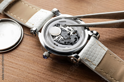 Foto Clockmaker repairing watch at table, closeup