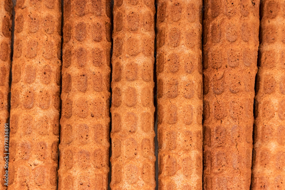 homemade Russian waffles, twisted into tubes, lie vertically in a row, golden brown wafers texture homemade Russian waffles, twisted into tubes, lie vertically in a row, golden brown wafers texture