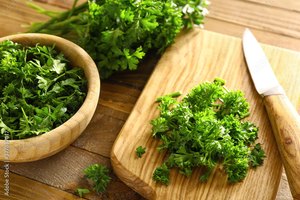 Fresh parsley, bowl, cutting board and knife on wooden background Fresh parsley, bowl, cutting board and knife on wooden background