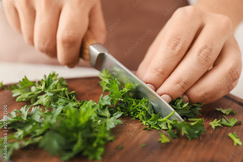 Woman cutting fresh parsley at table, closeup Woman cutting fresh parsley at table, closeup