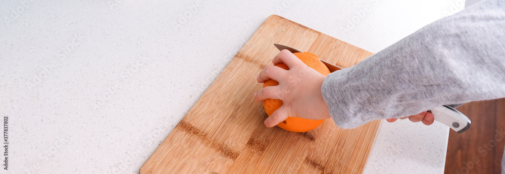 Boy's hands cutting fresh orange on kitchen Boy's hands cutting fresh orange on kitchen
