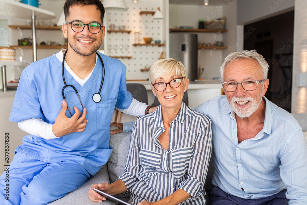 Portrait of male nurse with senior patients siting on sofa while being in a home visit. Portrait of male nurse with senior patients siting on sofa while being in a home visit.