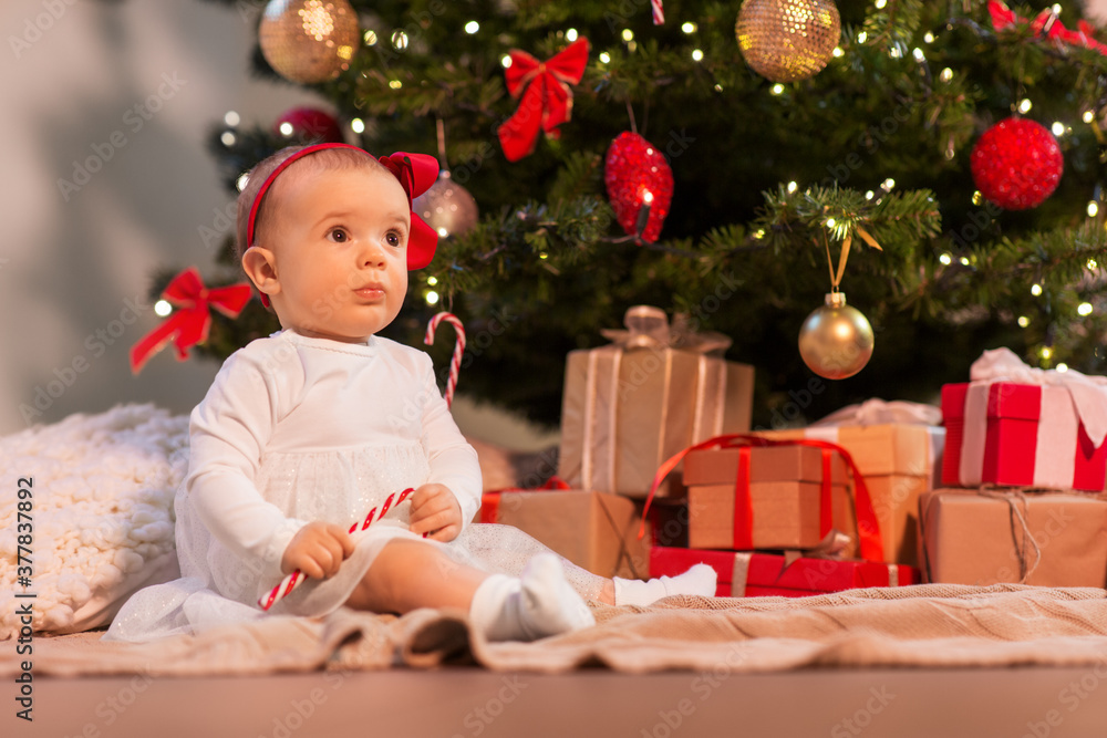 holidays and childhood concept - sweet baby girl at christmas tree with gifts at home holidays and childhood concept - sweet baby girl at christmas tree with gifts at home