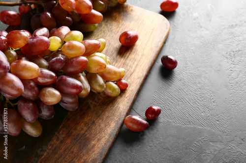 Board with ripe grapes on table, closeup