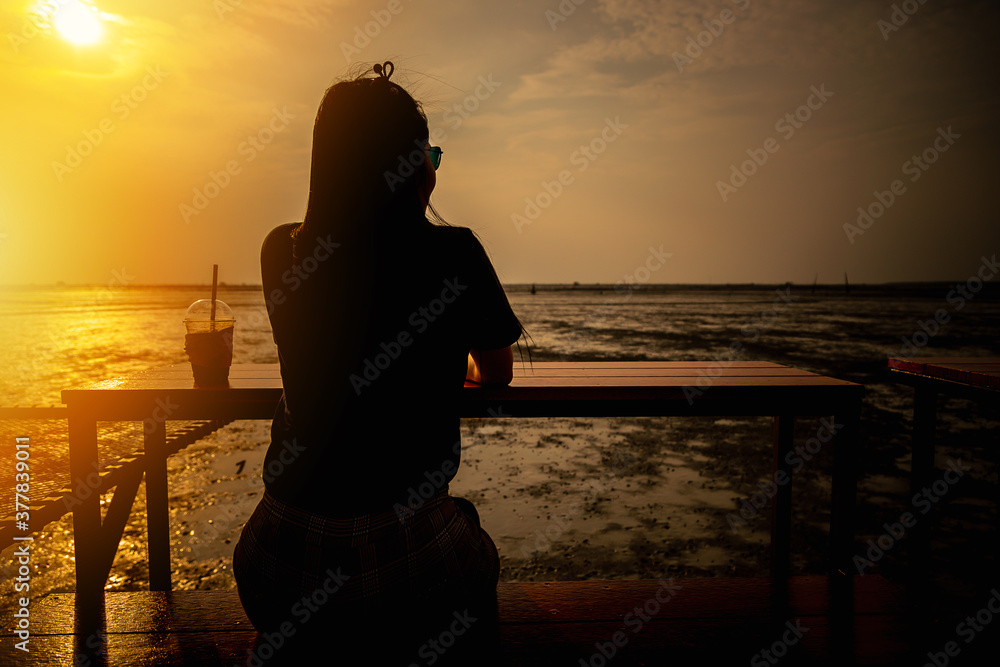 Women sitting and watching the sea at sunset