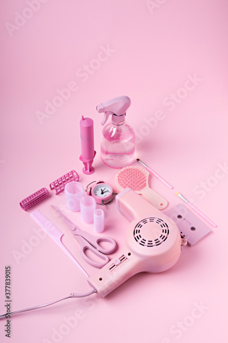 Creative layout made of hair dryer, scissors and accessories on pink background. Retro vintage 60's and 70's aesthetic with summer shadows. Flat lay.