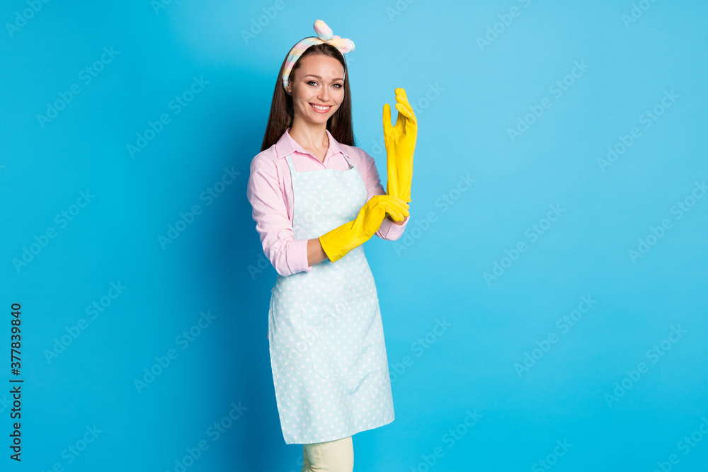 Portrait of nice confident girl wear yellow latex protective rubber gloves wash house clean prevent covid infection pandemic isolated over blue color background Portrait of nice confident girl wear yellow latex protective rubber gloves wash house clean prevent covid infection pandemic isolated over blue color background