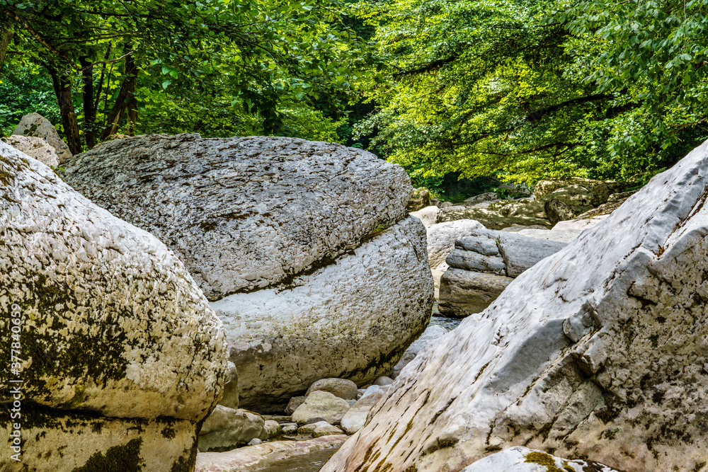 Big white stones with moss in the green forest with small river. Green forest Big white stones with moss in the green forest with small river. Green forest