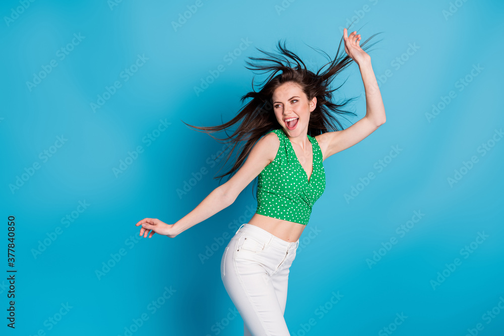 Naklejka premium Photo of excited energetic girl dance discotheque air wind blow hair raise hands wear tank-top trousers isolated over blue color background