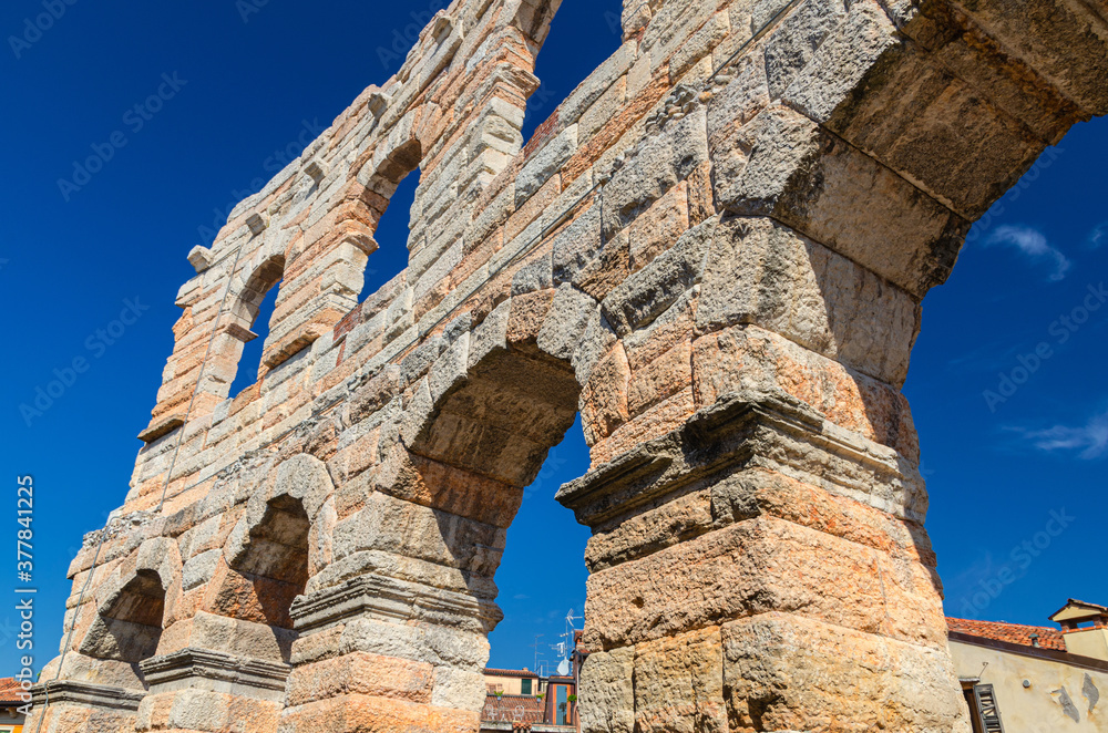 Limestone walls with arch windows of The Verona Arena in Verona city historical centre, Roman amphitheatre Arena di Verona ancient building, view from below, blue sky, Veneto Region, Northern Italy
