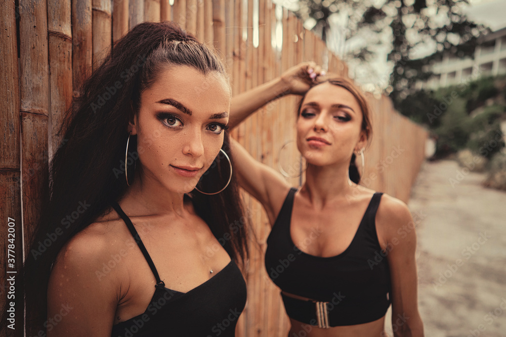 Two beautiful twin sisters Outdoor portrait. beautiful athletic slim bodied twin girls brunettes with long hair
