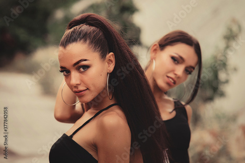 Obraz na płótnie Two beautiful twin sisters Outdoor portrait. beautiful athletic slim bodied twin girls brunettes with long hair w salonie