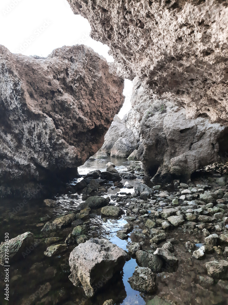 Stones of different sizes lying in the water near the rocks, sea Bay, the entrance to the cave. The concept of visiting unusual places and non-standard tourist routes