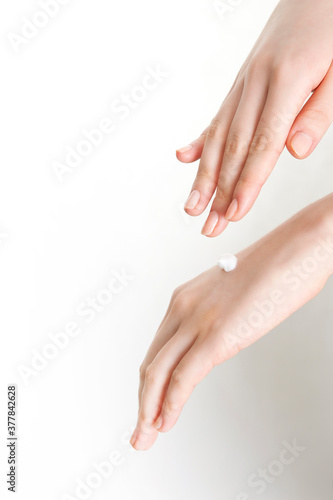woman applying lotion to her hands on white background © Image Republic