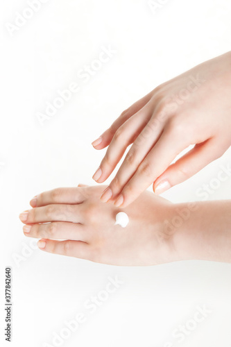 woman applying lotion to her hands on white background
