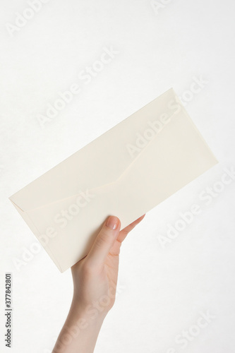 woman's hand holding envelope on white background