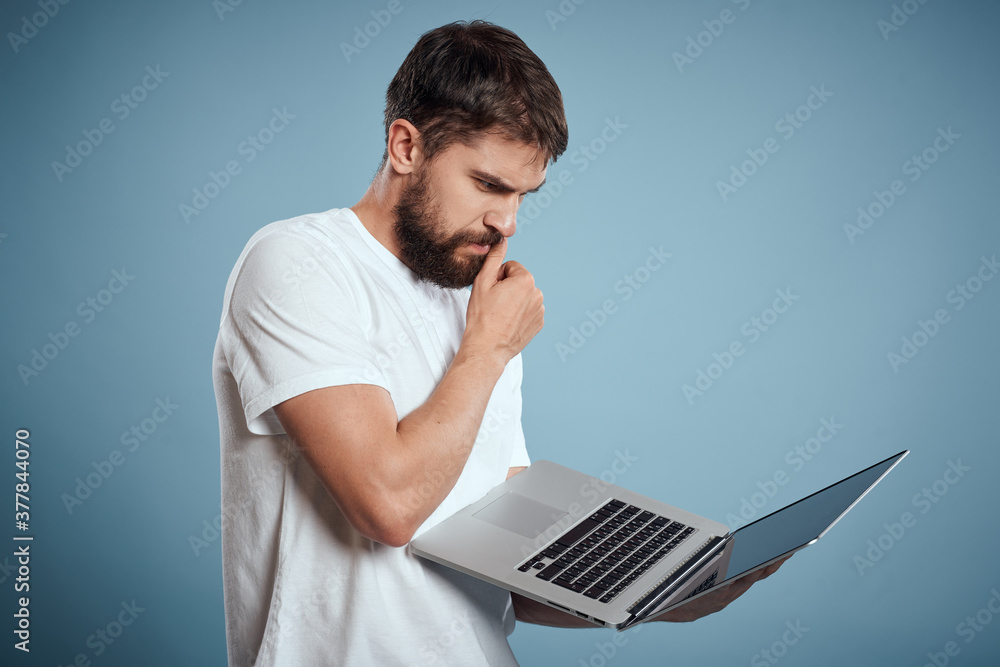 Emotional man with laptop in hands on blue background monitor keyboard internet model cropped view Emotional man with laptop in hands on blue background monitor keyboard internet model cropped view
