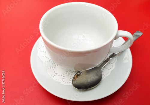 A tea cup with a spoon on a red