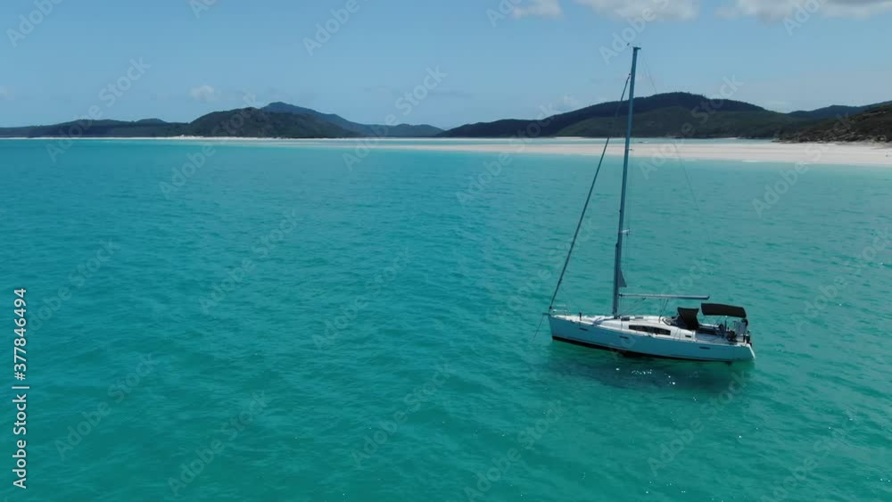A White Sailing Yacht sits anchored off the coast of Amazing White Haven Beach Australia, Drone Orbit and Flyover A White Sailing Yacht sits anchored off the coast of Amazing White Haven Beach Australia, Drone Orbit and Flyover