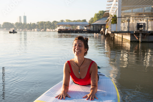 Woman practising downward facing dog pose during her yoga exercise on a paddle board