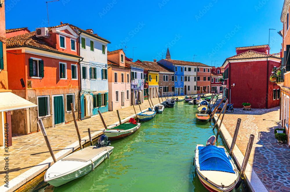 Colorful houses of Burano island. Multicolored buildings on fondamenta embankment of narrow water canal with fishing boats, Venice Province, Veneto Region, Northern Italy. Burano postcard