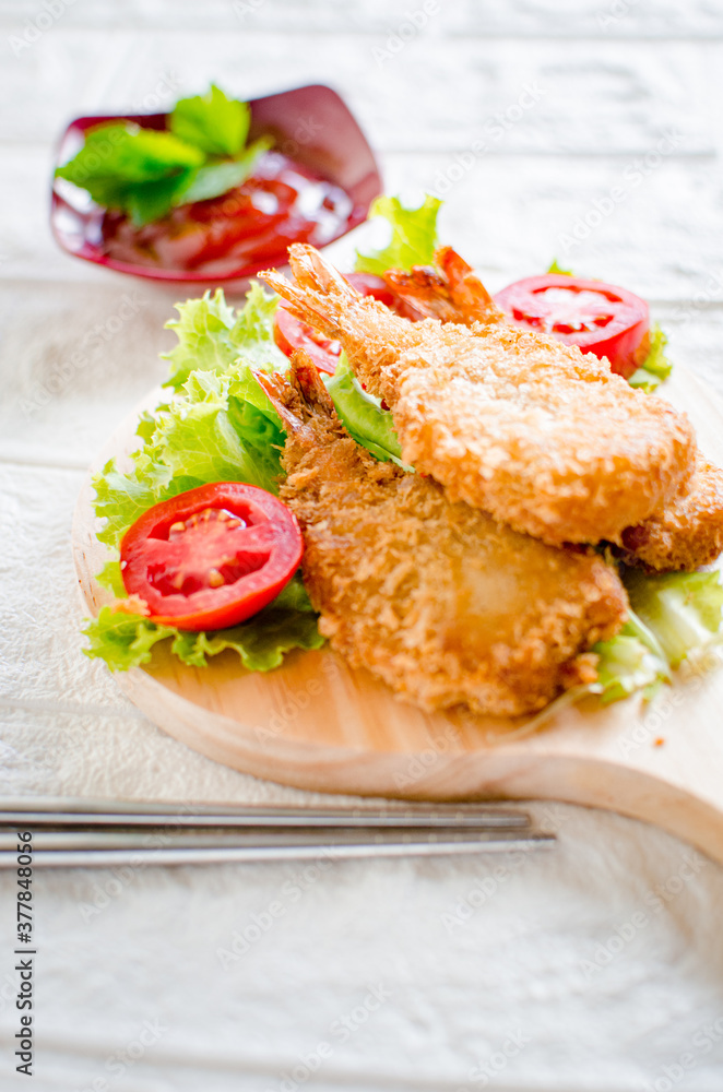 Butterfly ebi furai shrimp served with tomato and lettuce on a wooden chopping board along with ketchup
Butterfly ebi furai shrimp served with tomato and lettuce on a wooden chopping board along with ketchup