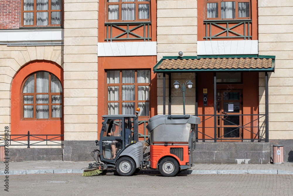 Gorki Gorod, Sochi, Russia. July 9, 2020 : a small orange utility car sweeps the streets of the city