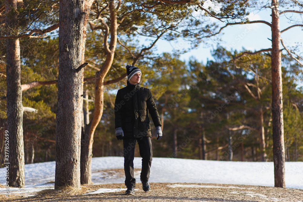 Young caucasian man in a warm winter clothes in the coniferous winter forest in north Russia.