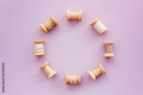 Wooden spools of thread for sewing on lilac background