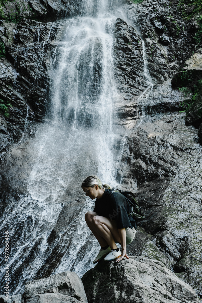 Obraz premium young woman on the background of a mountain waterfall with a ponytail 