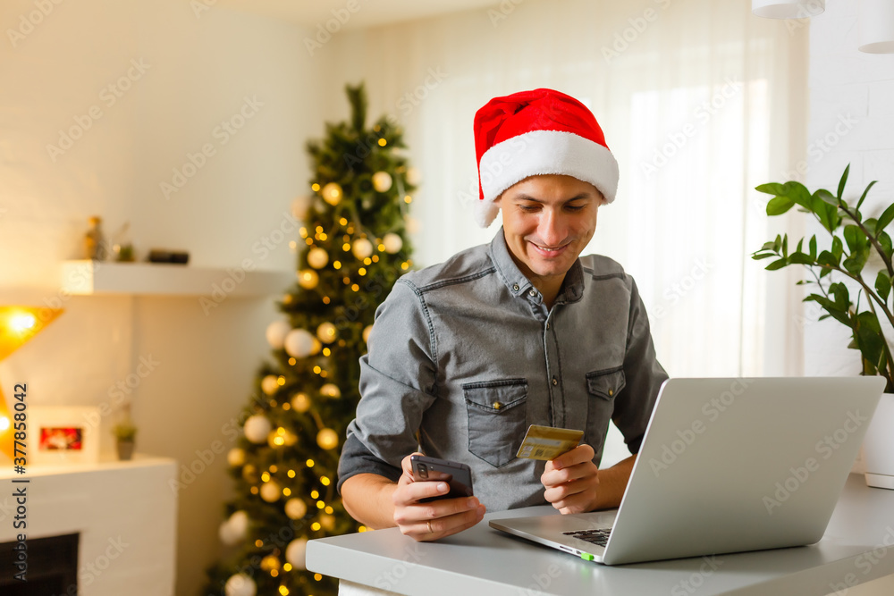 Young man shopping online with credit card at home for Christmas. Christmas shopping concept. Young man shopping online with credit card at home for Christmas. Christmas shopping concept.