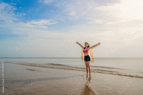 freedom woman in bikini walking with arms raised on sea beach