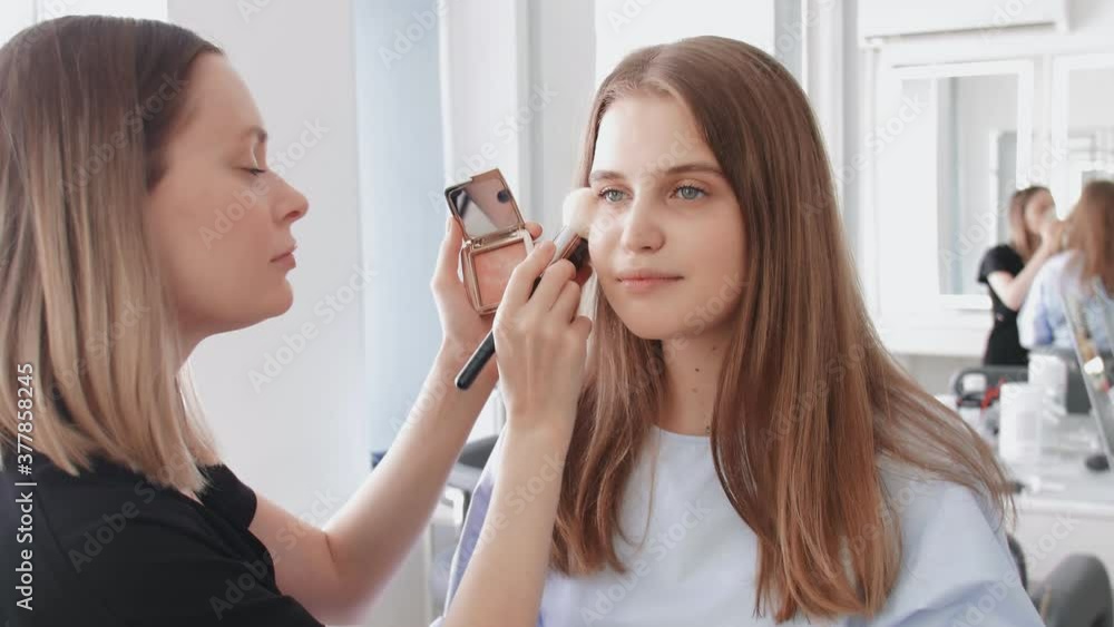 Professional make up artist uses big brush to apllies tone or powder Professional make up artist uses big brush to apllies tone or powder