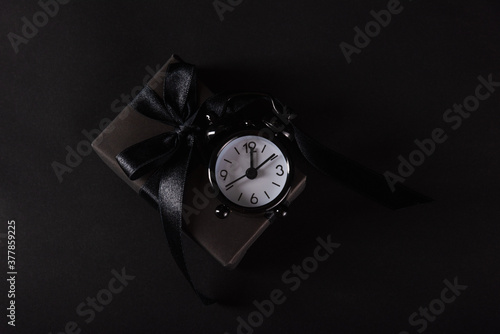 Wallpaper Mural Black Friday sale shopping concept, Top view of gift box wrapped in black paper and black bow ribbon and black alarm clock, studio shot on black background Torontodigital.ca
