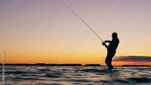 A man is getting a fish from the lake with a fishing rod