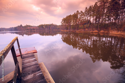 Sunset over the lake. Trees on the lakeshore. Serene lake in the evening. Nature landscape