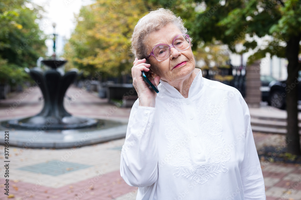 mature european woman talking on the phone in summer park