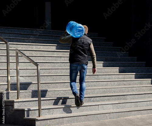 man carrying a bottle of water up the stairs © valeie