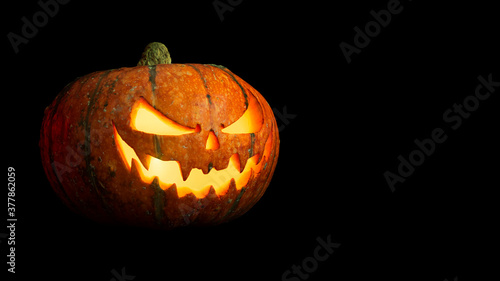halloween pumpkin with glowing eyes and mouth isolated on black background closeup with copy space © NIKOLAI
