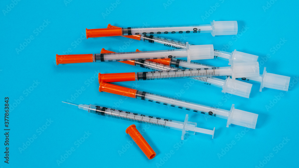 Insulin vial and syringe on blue background. Health care, doctor, clinic or hospital, medical concept. World diabetes day. Ready for vaccine injection. Pain treatment, illegal use, vaccination Insulin vial and syringe on blue background. Health care, doctor, clinic or hospital, medical concept. World diabetes day. Ready for vaccine injection. Pain treatment, illegal use, vaccination