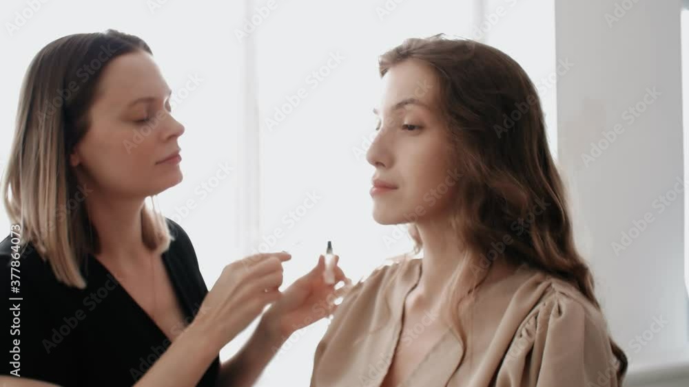 Makeup artist combs the model's eyebrows with a special eyebrow brush Makeup artist combs the model's eyebrows with a special eyebrow brush