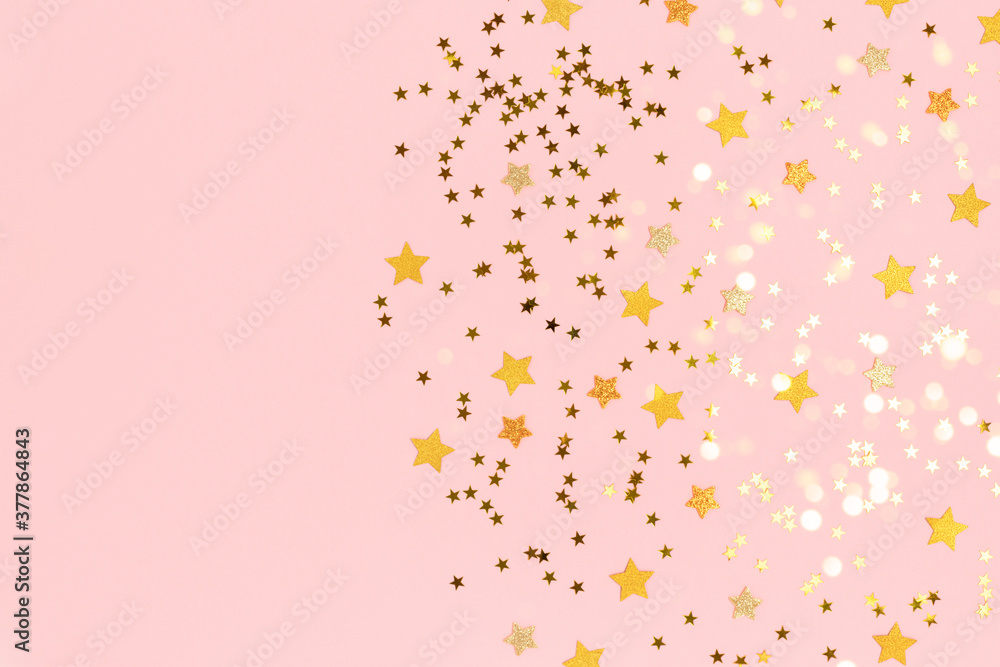 Gold stars confetti scattered on a pink pastel background. Holidays colorful composition with copy space.